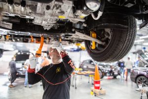 Training_instructor_mechanic_testing_probing_measuring_Kia_Niro_EV_underside